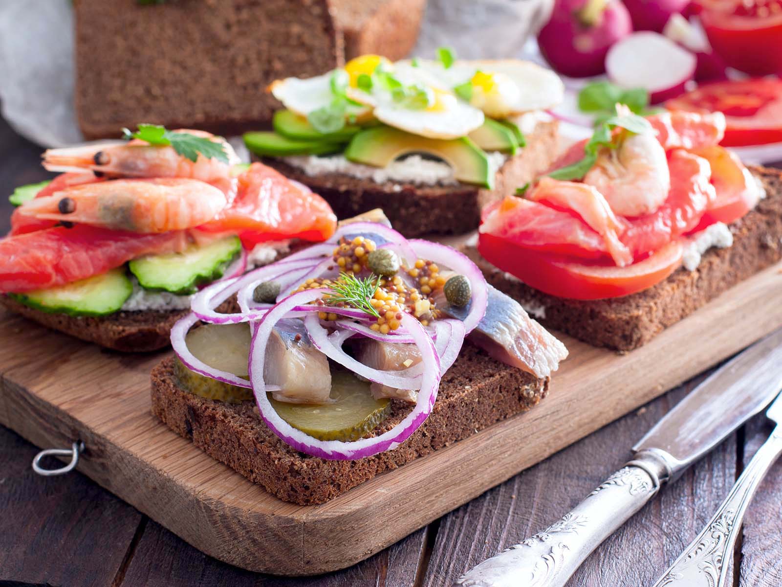 Open sandwich with salted herring, cucumber, red onion, mustard on rye bread, selective focus